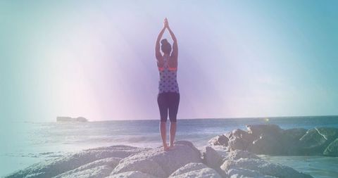 Woman Practicing Yoga by Ocean in Sunrise Glow