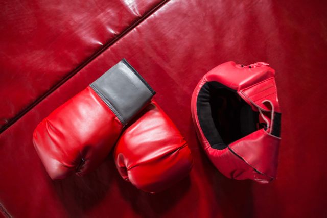Pair of boxing gloves and headgear on red surface