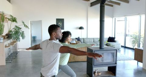 Couple practicing yoga in modern living room for wellness