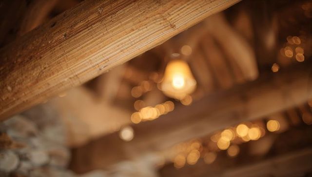 Rustic barn rafters with diagonal timber beam, filament bulb and warm bokeh lights