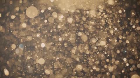 Golden bokeh particles drifting toward center in dark studio with warm backlight