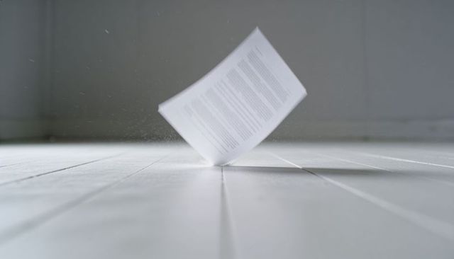 Floating document hovering above white wooden floor creating minimalist motion and dust