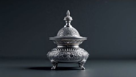 Ornate silver frankincense container with engraved patterns on dark tabletop