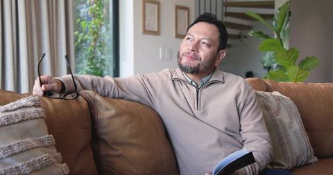 Senior Man in Cozy Living Room Contemplating with Notebook