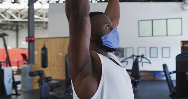 Man wearing face mask lifting weights in gym representing modern workout routines - Download Free Stock Images Pikwizard.com