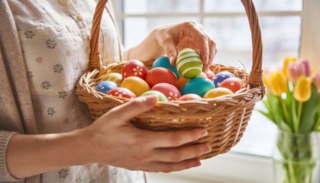Spring easter basket holding colorful hand-painted eggs by sunlit window
