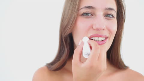 Woman Smiling While Applying Lip Balm on White Background
