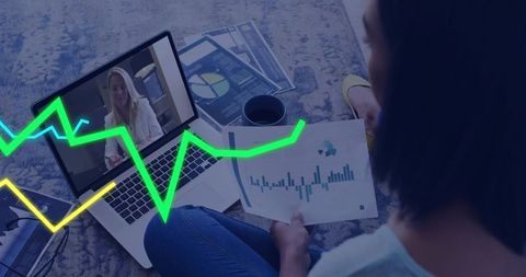 Remote analyst reviewing financial charts during virtual meeting with laptop and printouts