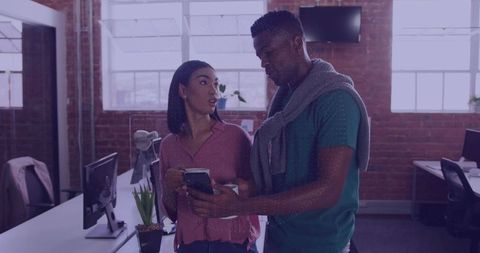 Coworkers engaging in office collaboration with smartphones