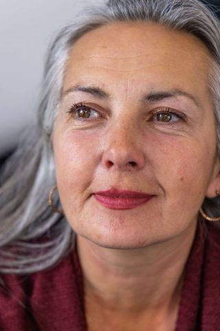 Serene senior woman looking upward with silver hair, burgundy knit and mauve lipstick