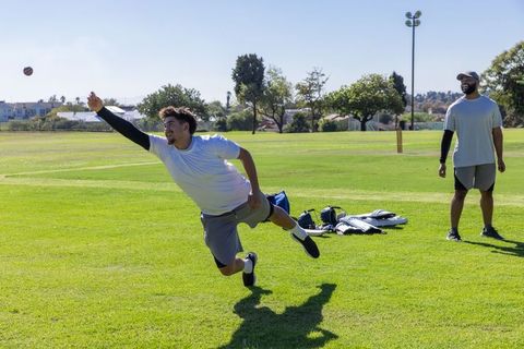 Diving fielder catching cricket ball during sunny outdoor practice session