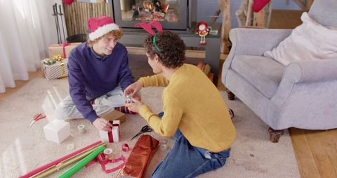 Joyful Couple Wrapping Christmas Gifts in Cozy Living Room
