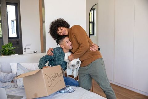 Male partners embracing during donation box packing in cozy bedroom