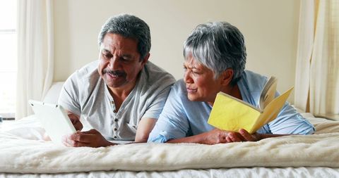 Middle-aged Latino Couple Enjoying Leisure Time with Tablet and Book