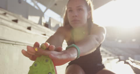 Female Athlete Stretching in Sunlit Stadium Ready for Training Session