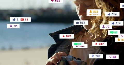 Woman adjusting camera by waterfront with floating social media notifications and sunny bokeh