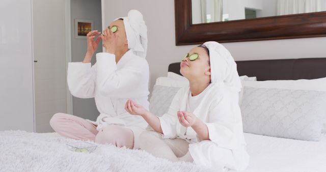 Image of happy asian mother and daughter in robes doing cucumber mask and resting - Download Free Stock Photos Pikwizard.com