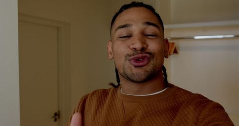 Man in brown sweater making a silly face indoors