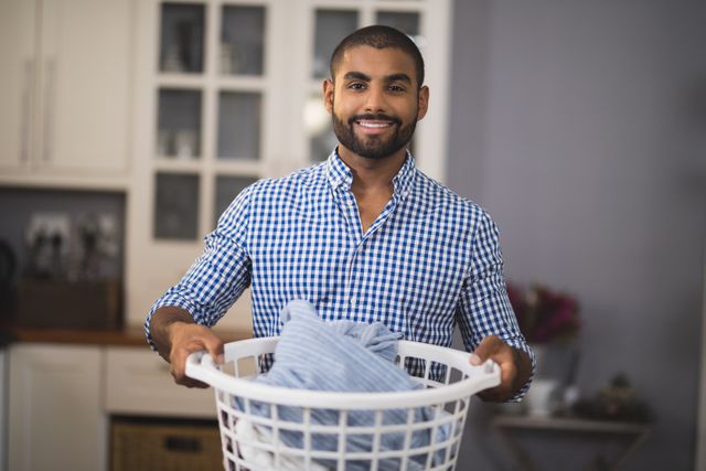 Portrait of smiling young man holding laundry basket at home