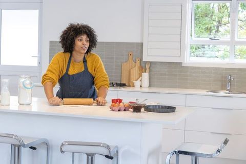 Home baker rolling dough on kitchen island in modern bright minimalist kitchen