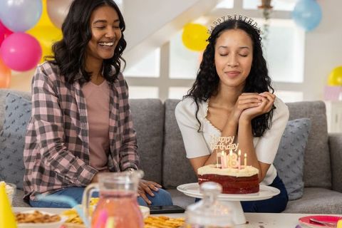 Diverse friends celebrating birthday with red velvet cake on cozy gray couch