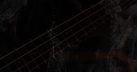 Moody close-up of electric guitar neck with grunge texture and dim studio lighting