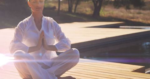 Serene Woman Meditating in Sunlit Outdoor Setting