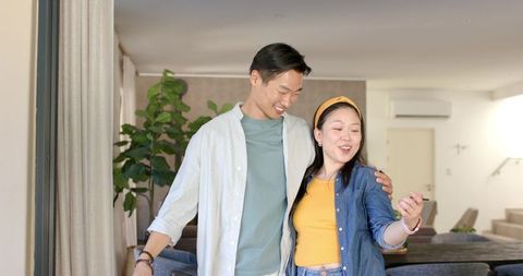 Young asian couple enjoying smartphone moment in modern bright living room at home