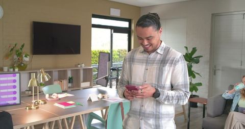 Professional checking smartphone in bright collaborative coworkorking space with greenery