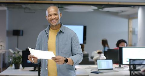 African American man presenting papers to collaborative team in modern open office