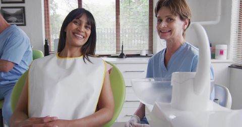 Smiling female patient receiving dental checkup with friendly dentist in modern clinic
