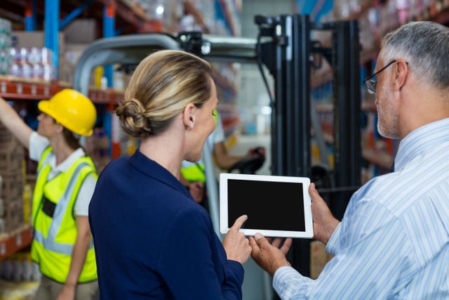 Warehouse manager and client discussing over digital tablet in warehouse