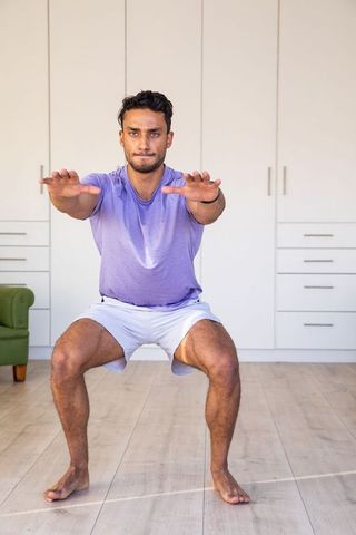 Young Indian Man Performing Squat Exercise in Modern Home