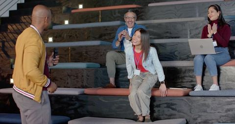 Casual conference presenting in tiered amphitheater with engaged attendees and laptop
