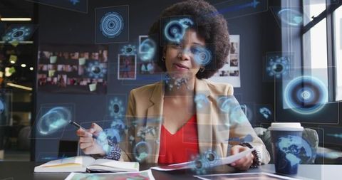 Business analyst reviewing documents and writing notes with holographic data overlays