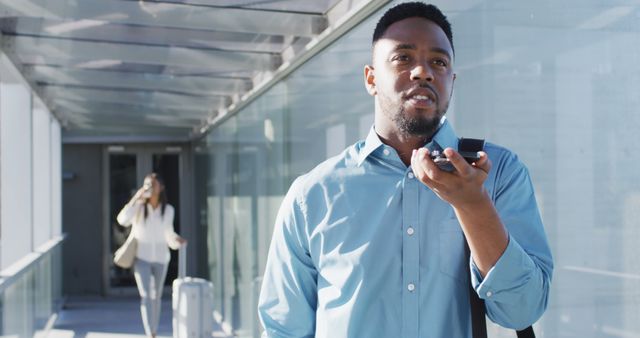 Image of african american man walking and using smartphone. business professionals and working in office concept.