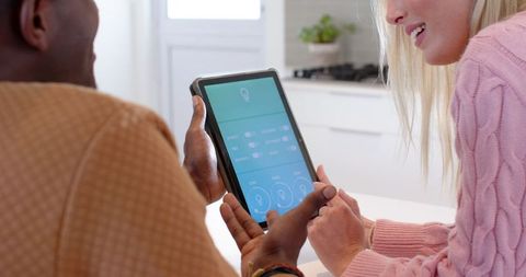 Couple using smart home interface on tablet in modern kitchen