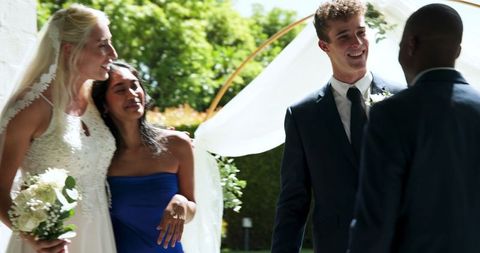Joyful Newlyweds with Wedding Party Embracing Outdoors