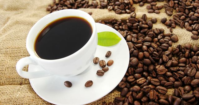A white cup of black coffee sits amidst scattered coffee beans, with copy space - Download Free Stock Photos Pikwizard.com
