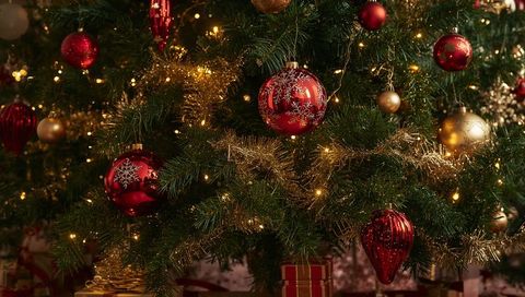 Glowing Christmas tree with red baubles and gold tinsel, warm lights and cozy bokeh