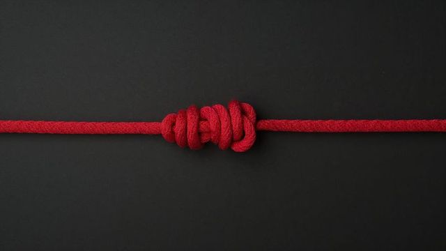 Intricately tied red rope knot on black background
