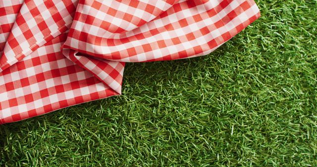 Close up of red and white checkered blanket on grass with copy space. Picnic day, food and nature concept.