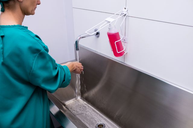 Image depicts a female surgeon washing hands in a hospital, highlighting importance of hygiene in medical settings. Useful for healthcare articles, infection control promotions, or medical training materials.
