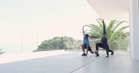 Embracing outdoor wellness: friends lunging by modern coastal retreat