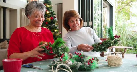 Senior mother and daughter crafting christmas wreaths together