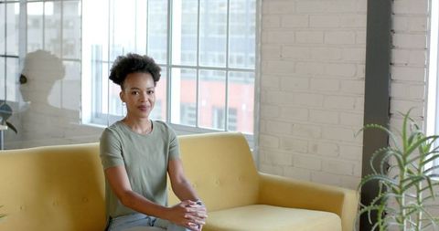 Confident Businesswoman Sitting on Yellow Sofa in Bright Office