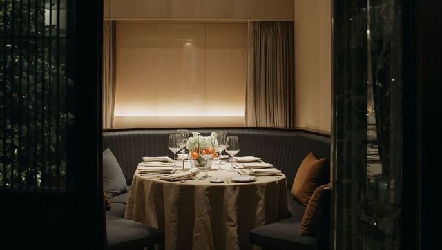 Private booth dining with round linen table, elegant glassware, citrus centerpiece, ambient light