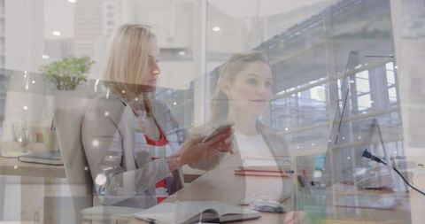 Businesswomen collaborating at desk in modern office environment