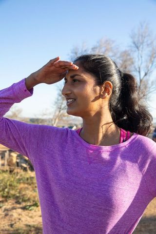 Active Indian Woman in Pink Sportswear Blocking Sunlight Outdoors