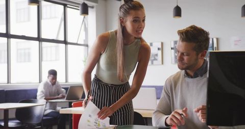 Young Professional Collaborating on Project with Colleague in Modern Office